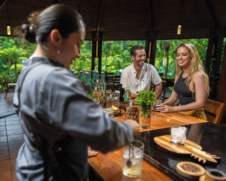 Bartender preparing drinks for smiling couple at an open bar at Tabacón Thermal Resort & Spa