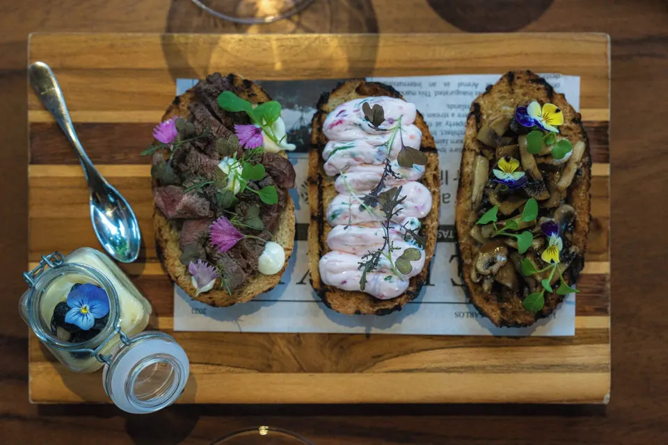 Three gourmet crostini with edible flowers on a wooden board at Tabacón Thermal Resort & Spa