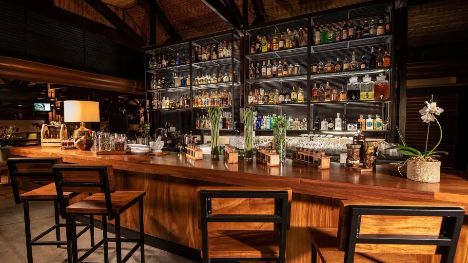 Polished wooden bar with backlit liquor shelves at Tabacón Thermal Resort & Spa