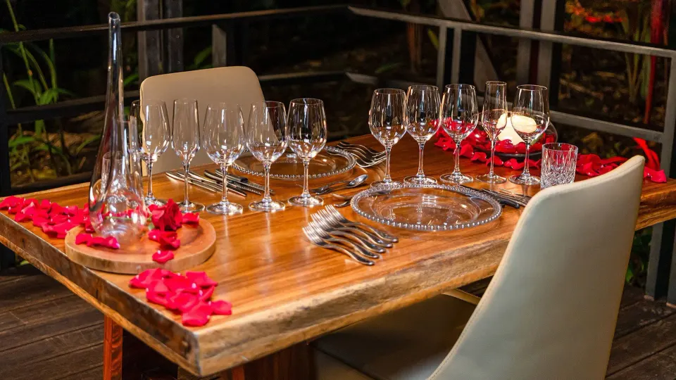 Outdoor wooden dining table set with glassware and rose petals at Tabacón Thermal Resort & Spa