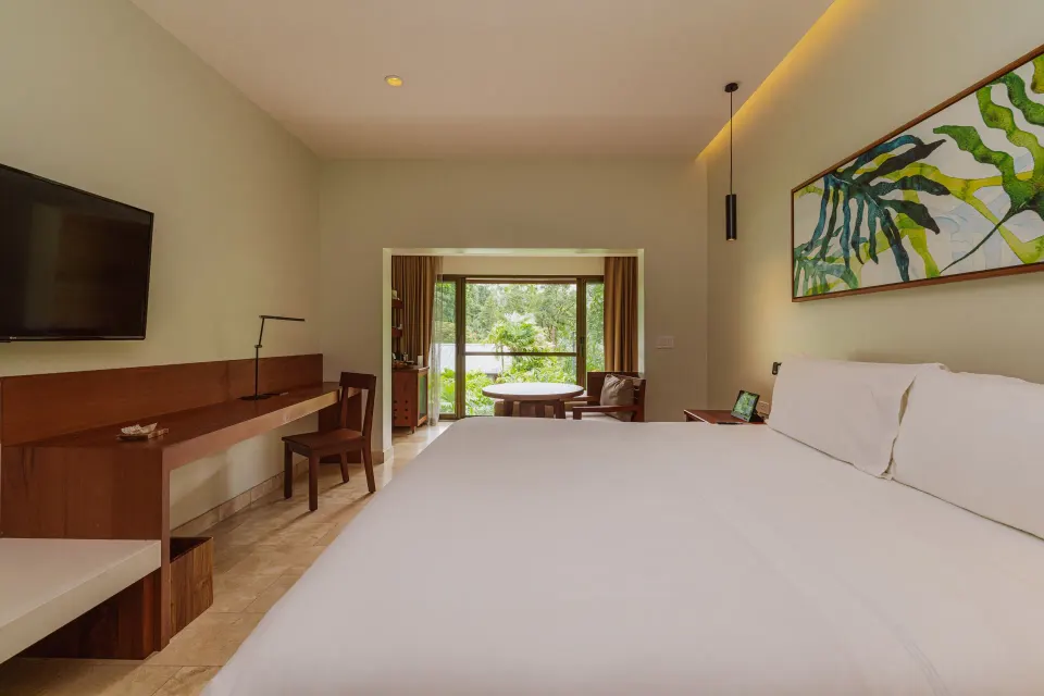Orchid Room king bed with desk and balcony opening at Tabacón Thermal Resort & Spa