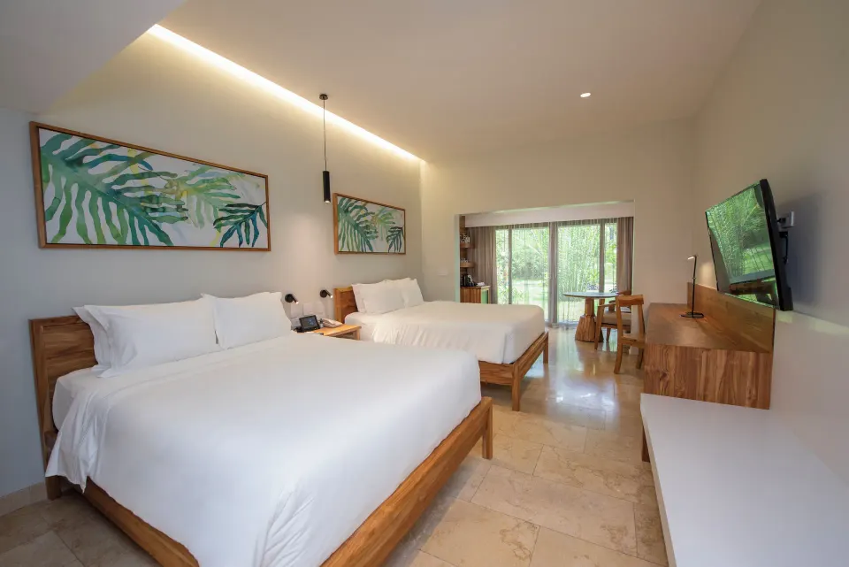 Orchid Room interior with two beds, wood furnishings and sliding glass doors at Tabacón Thermal Resort & Spa