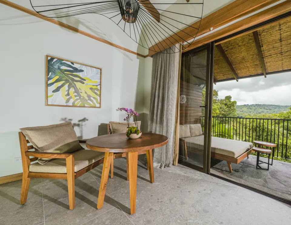 Seating area and balcony view in Rainforest King Bed Room at Tabacón Thermal Resort & Spa