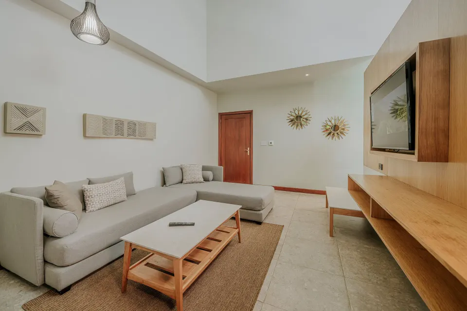 Living area with L-shaped sofa and TV in a Tabacón Suite King Bed Room at Tabacón Thermal Resort & Spa