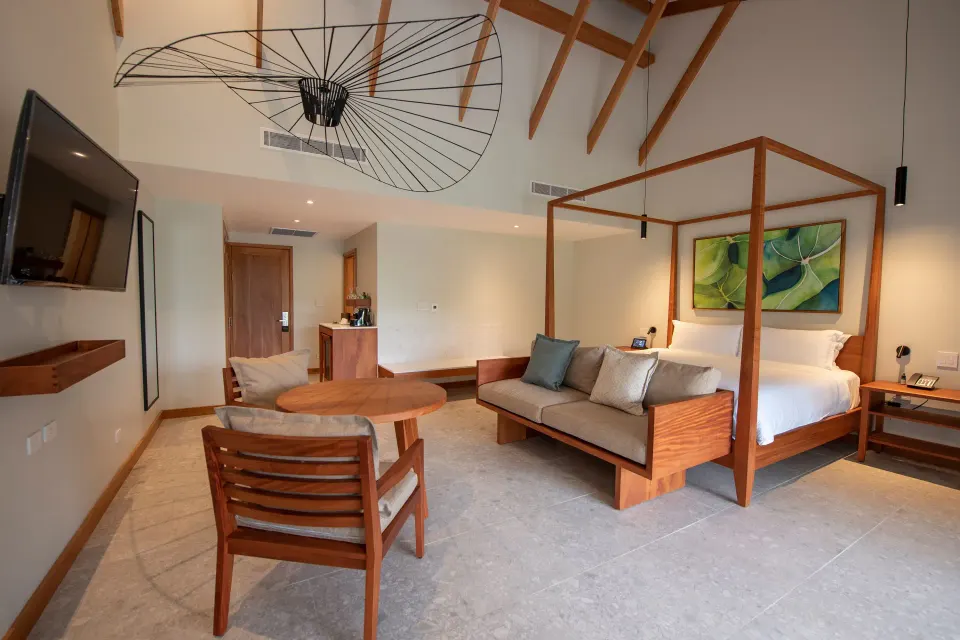Volcano View Suite bedroom and seating area with canopy bed at Tabacón Thermal Resort & Spa