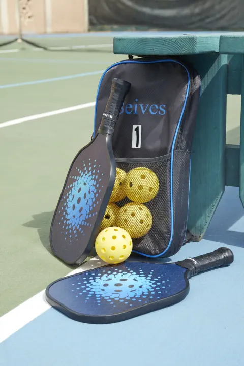 Pickleball paddles and balls beside a court bench at Tamarijn Aruba.