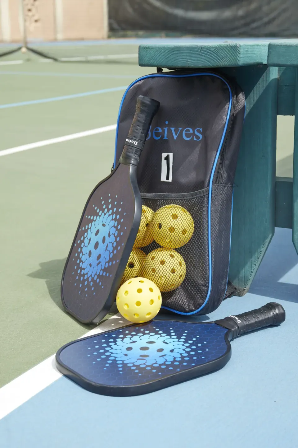 Pickleball paddles and balls beside a court bench at Tamarijn Aruba.