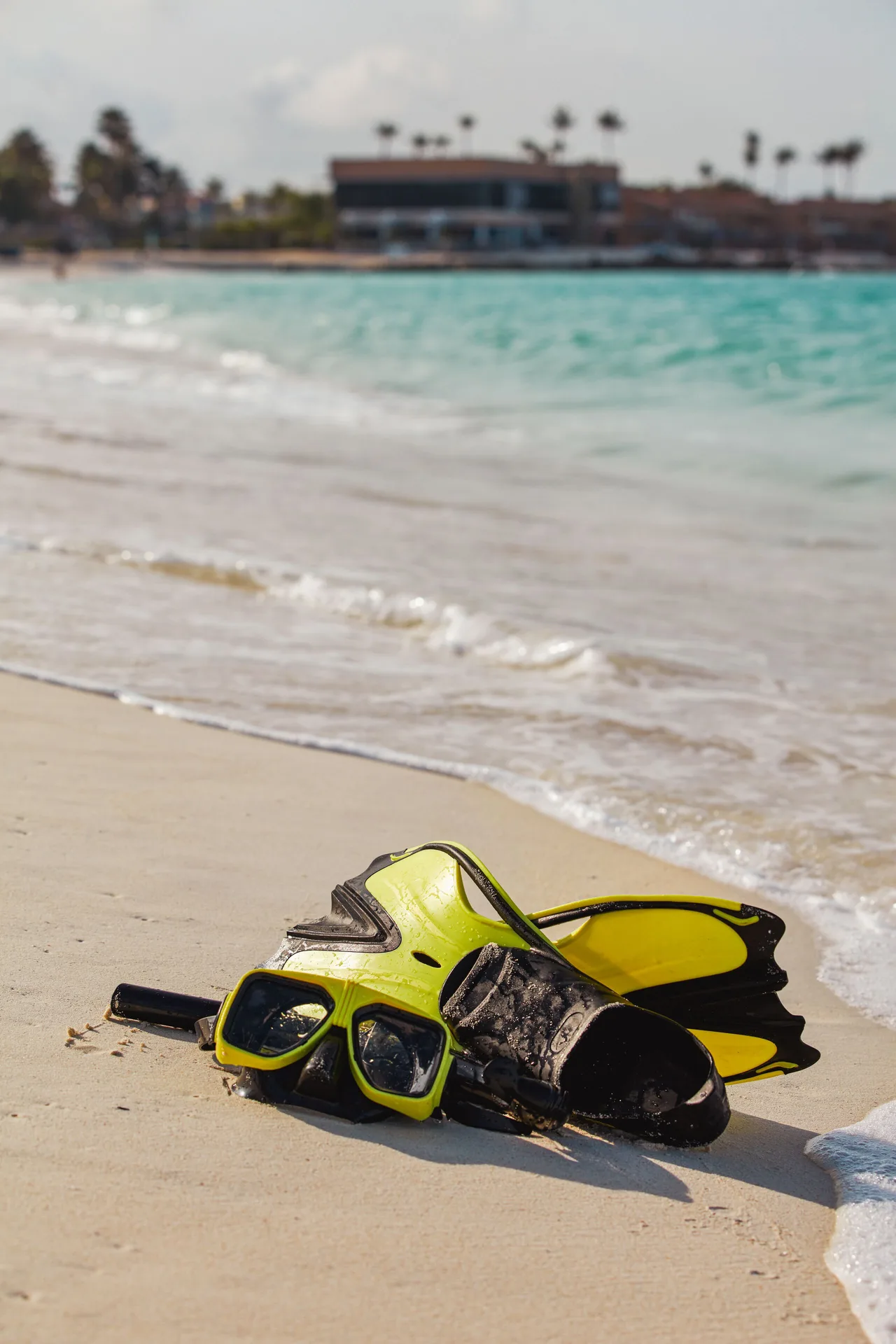 Snorkel mask and fins resting on the sandy beach at Tamarijn Aruba.