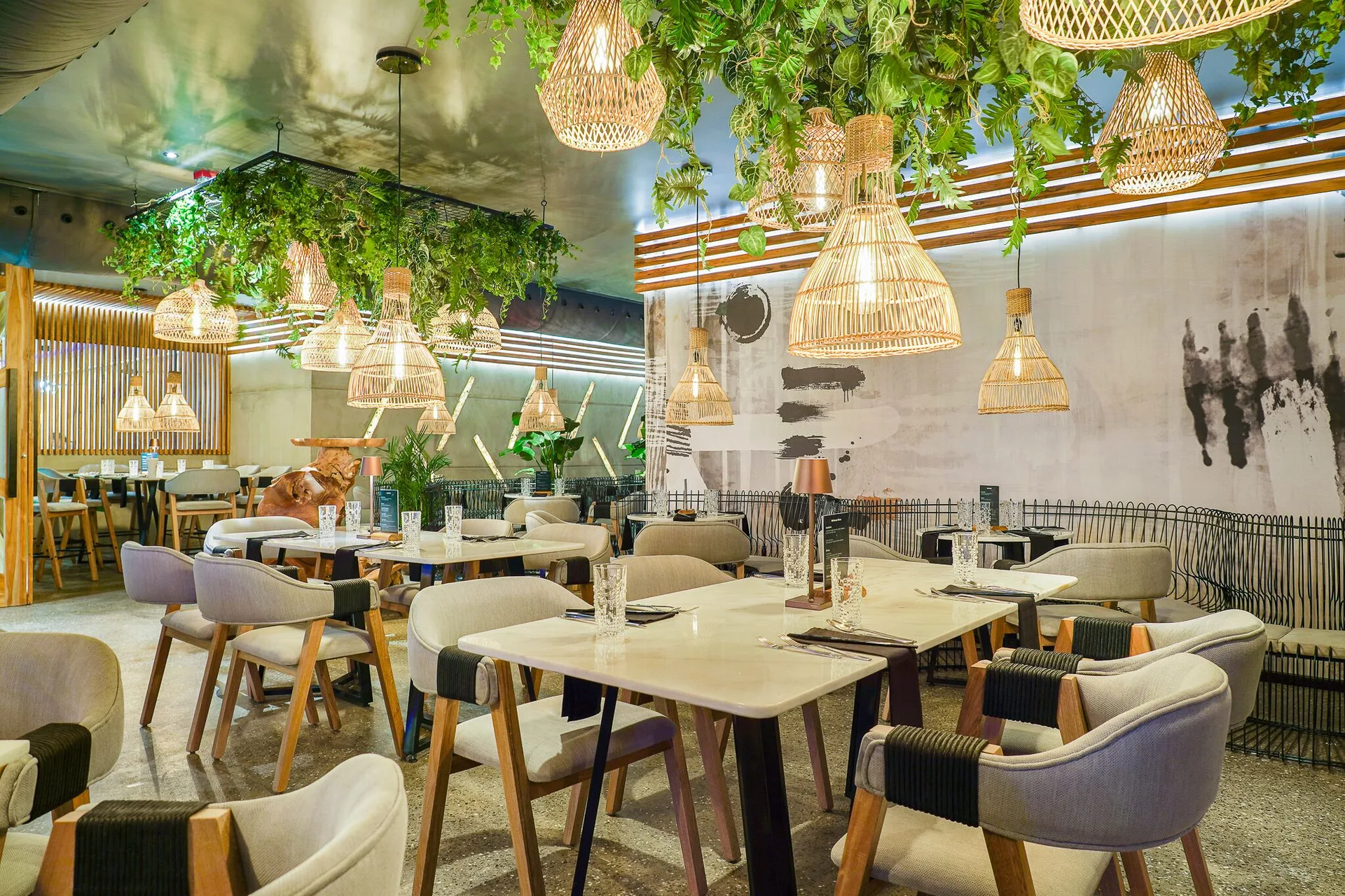 Modern dining room with rattan lights and greenery at Tamarijn Aruba.