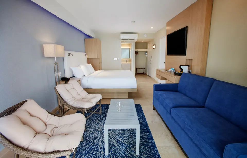 Premium Oceanfront Room with king bed, sofa, and lounge chairs at Tamarijn Aruba.