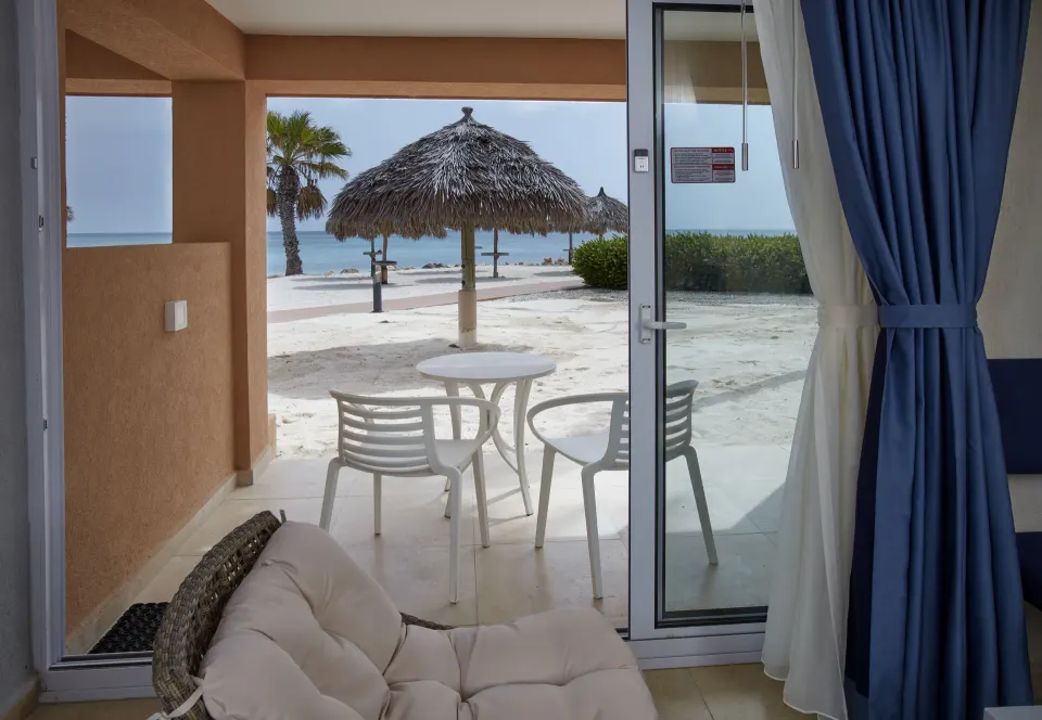 Premium Oceanfront Room patio with beach and palapa view at Tamarijn Aruba.