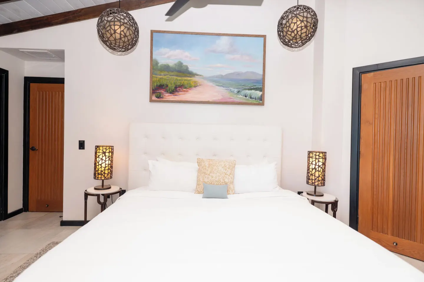 King bed centered between wood doors in a guest room at Tamarind Hills Resort & Villas.