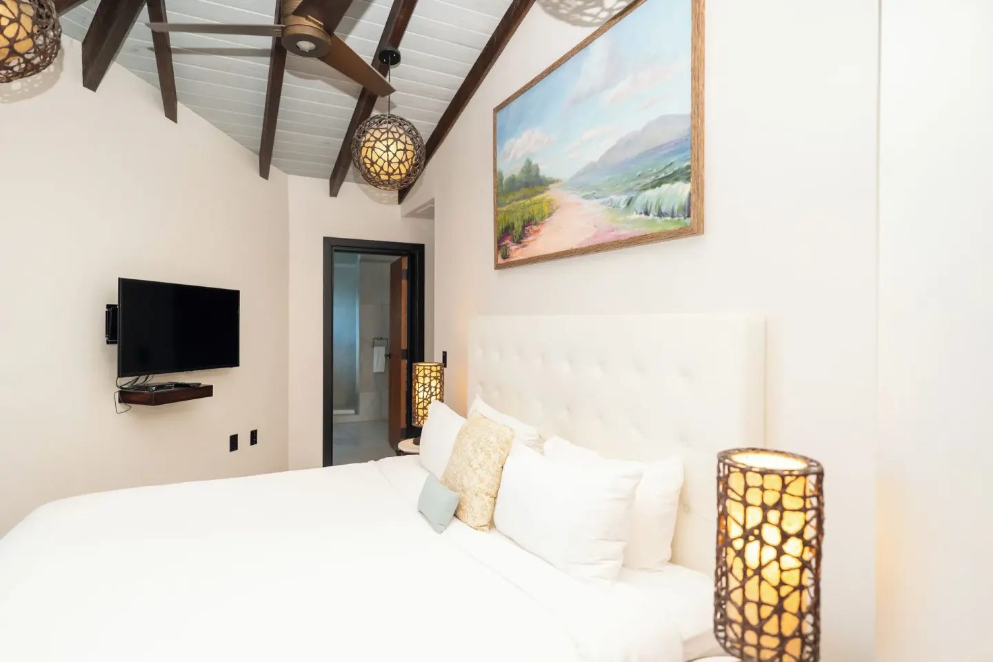 Guest room king bed with wall-mounted TV at Tamarind Hills Resort & Villas.