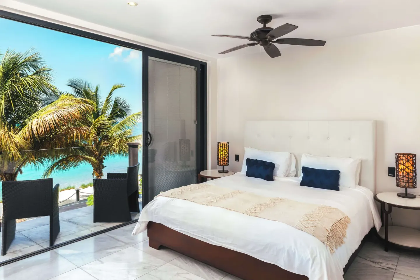 King-bed guest room with balcony and palm-framed sea view at Tamarind Hills Resort & Villas.