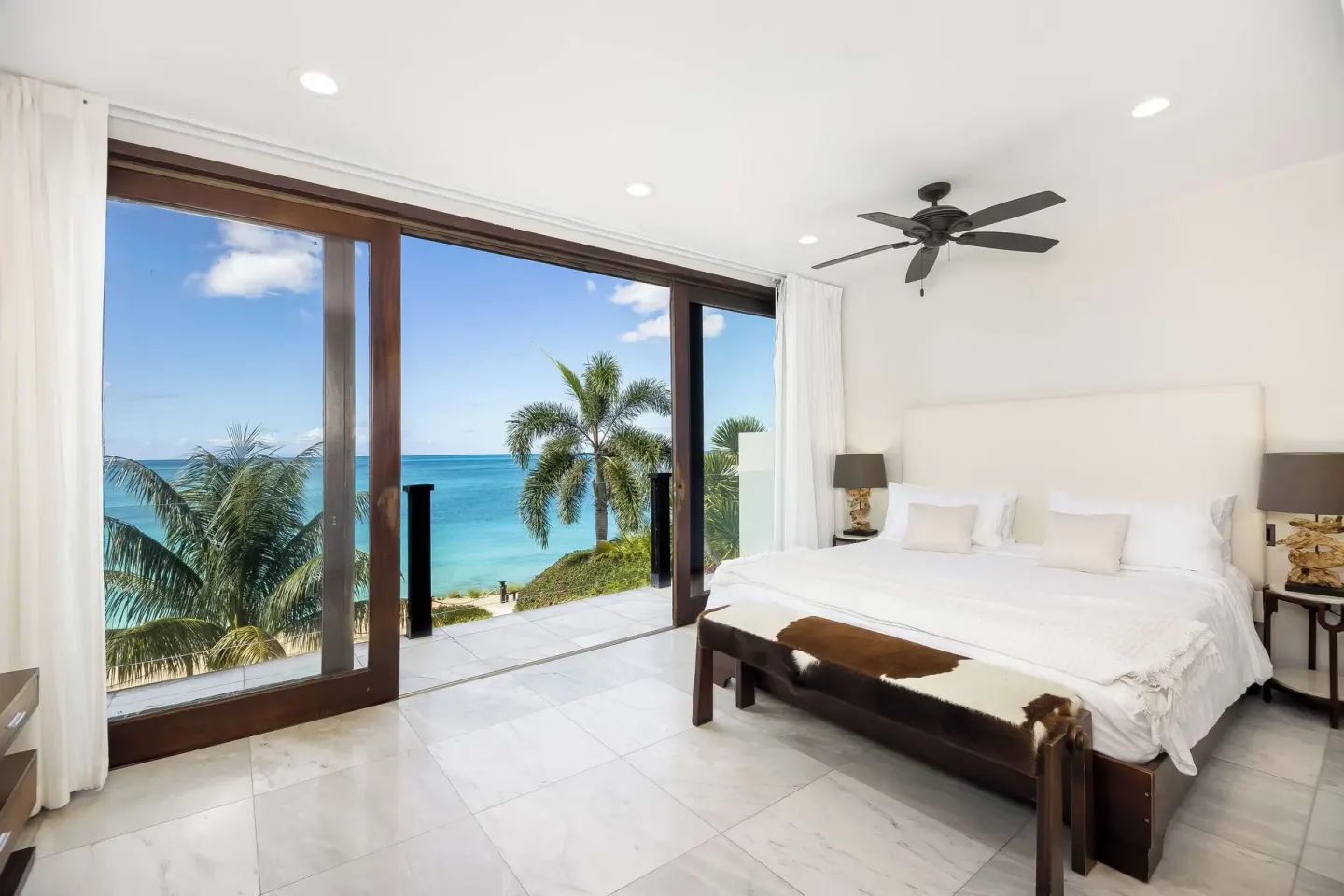 King-bed guest room with glass doors and ocean view at Tamarind Hills Resort & Villas.