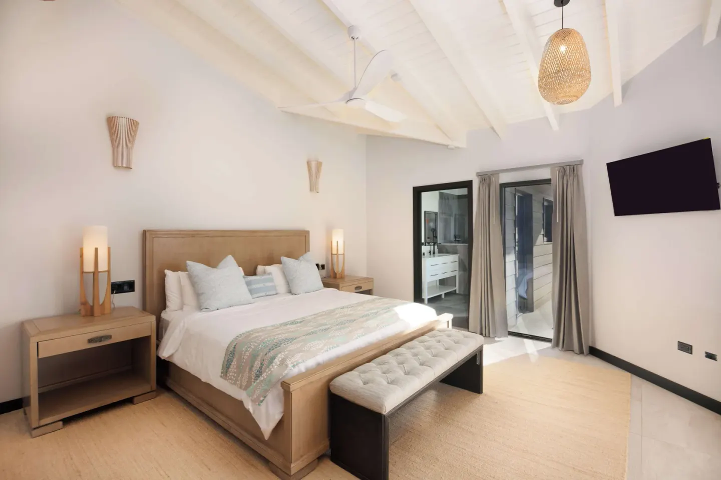 King-bed guest room with vaulted ceiling and wall-mounted TV at Tamarind Hills Resort & Villas.
