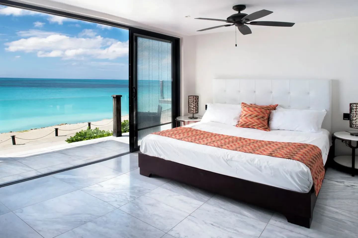 King-bed oceanfront guest room with terrace doors at Tamarind Hills Resort & Villas.