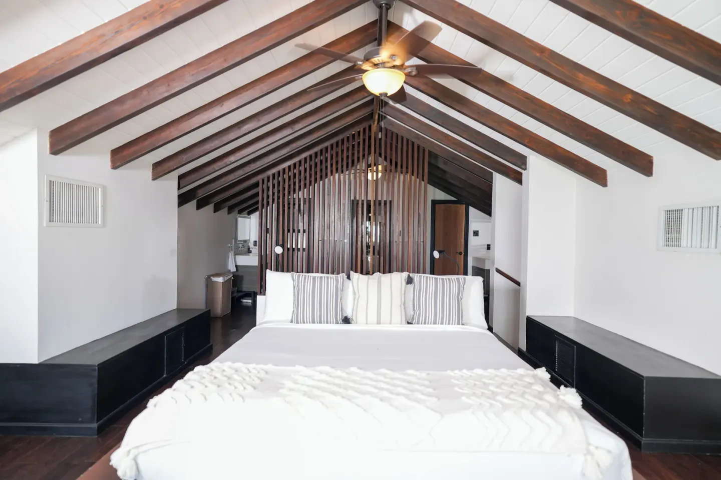 Loft-style king bed beneath exposed beams at Tamarind Hills Resort & Villas.