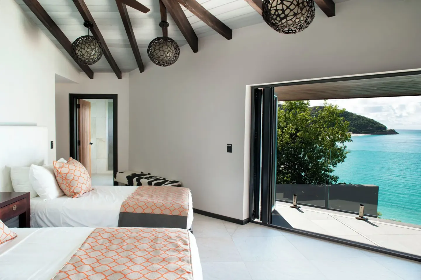Twin bedroom with open doors to the sea at Tamarind Hills Resort & Villas.
