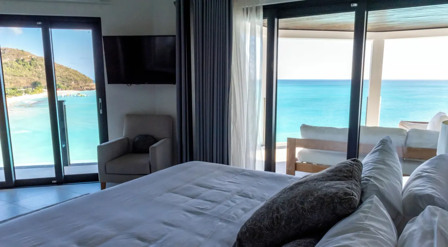 King bedroom with ocean-facing balcony at Tamarind Hills Resort & Villas.