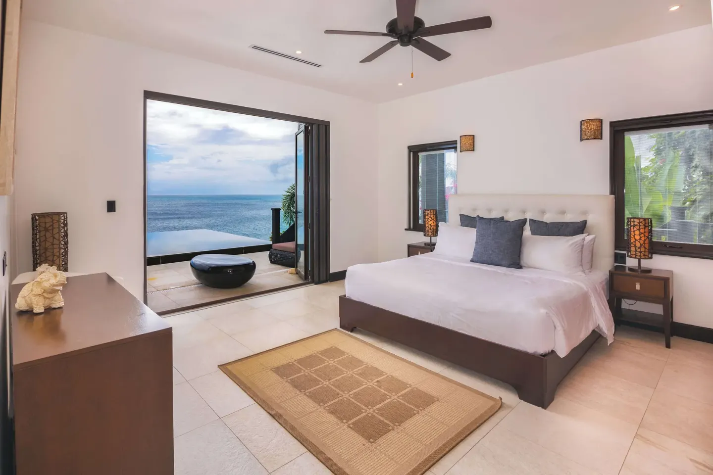 King bed guest room with terrace seating and ocean view at Tamarind Hills Resort & Villas.