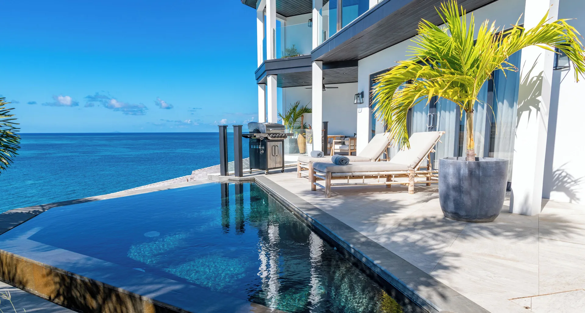 Oceanfront pool terrace with loungers and grill at Tamarind Hills Resort & Villas.
