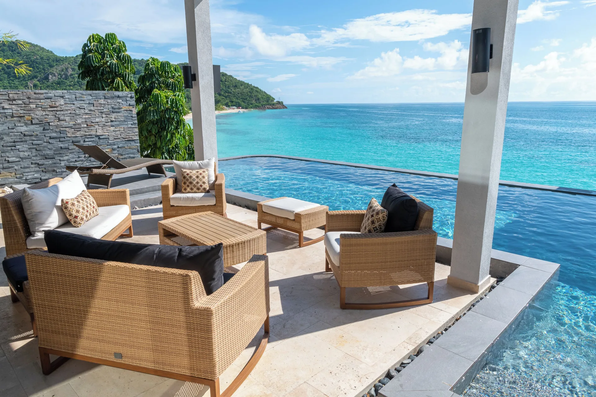 Oceanfront pool terrace with wicker seating at Tamarind Hills Resort & Villas.