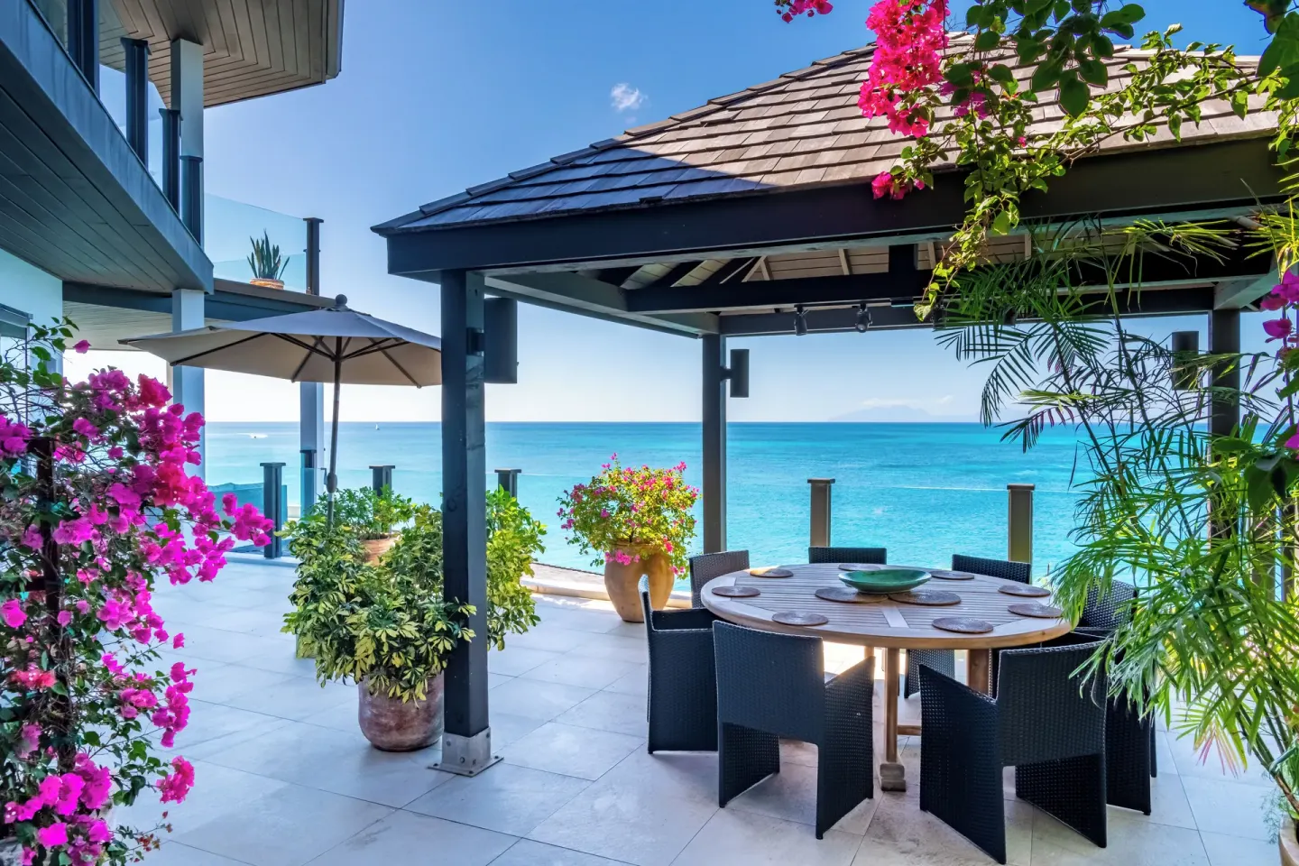 Oceanfront patio dining table with flowering plants at Tamarind Hills Resort & Villas.