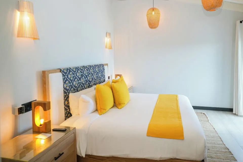Ocean 19 king bed with yellow accents and bedside lighting at Tamarind Hills Resort & Villas.