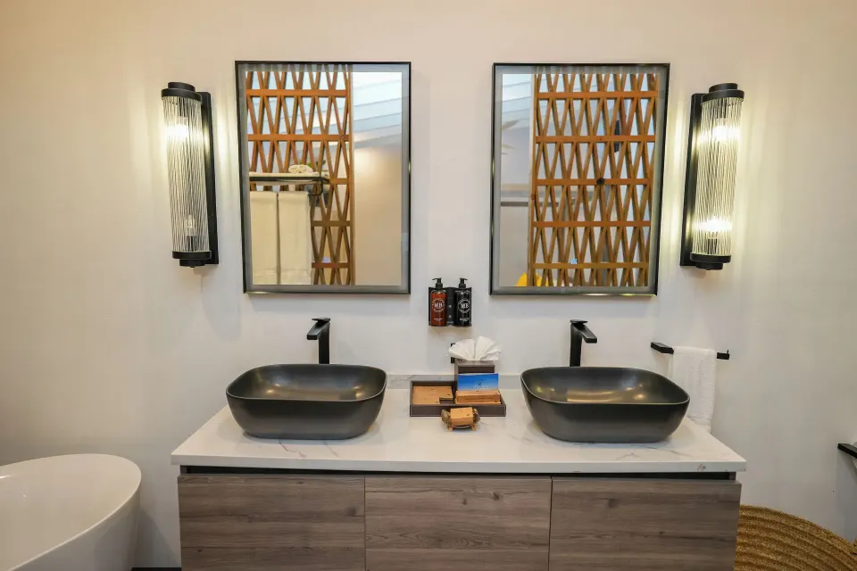 Double-sink bathroom vanity in Room 19 at Tamarind Hills Resort & Villas with mirrors and wall lights.