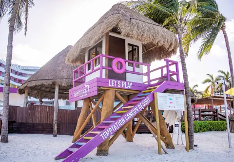 Purple beach lifeguard tower with thatched roof at Temptation Cancún.