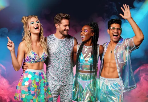 Guests in iridescent party outfits pose against colorful smoke at Temptation Cancún.