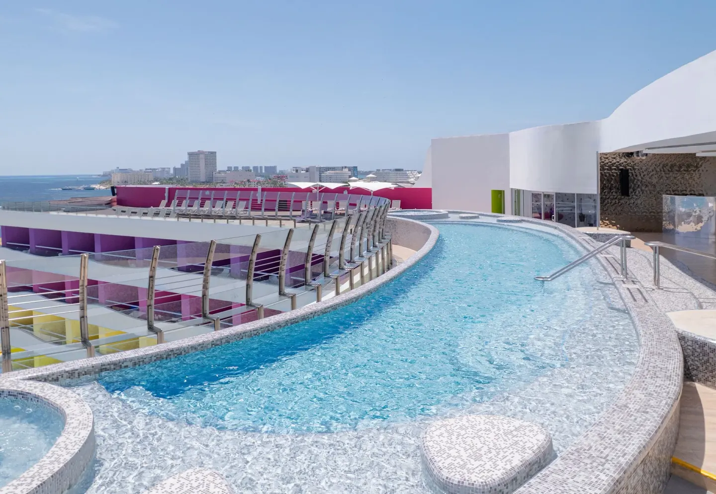 A curved rooftop pool with glass railings overlooks Cancun at Temptation Cancún.