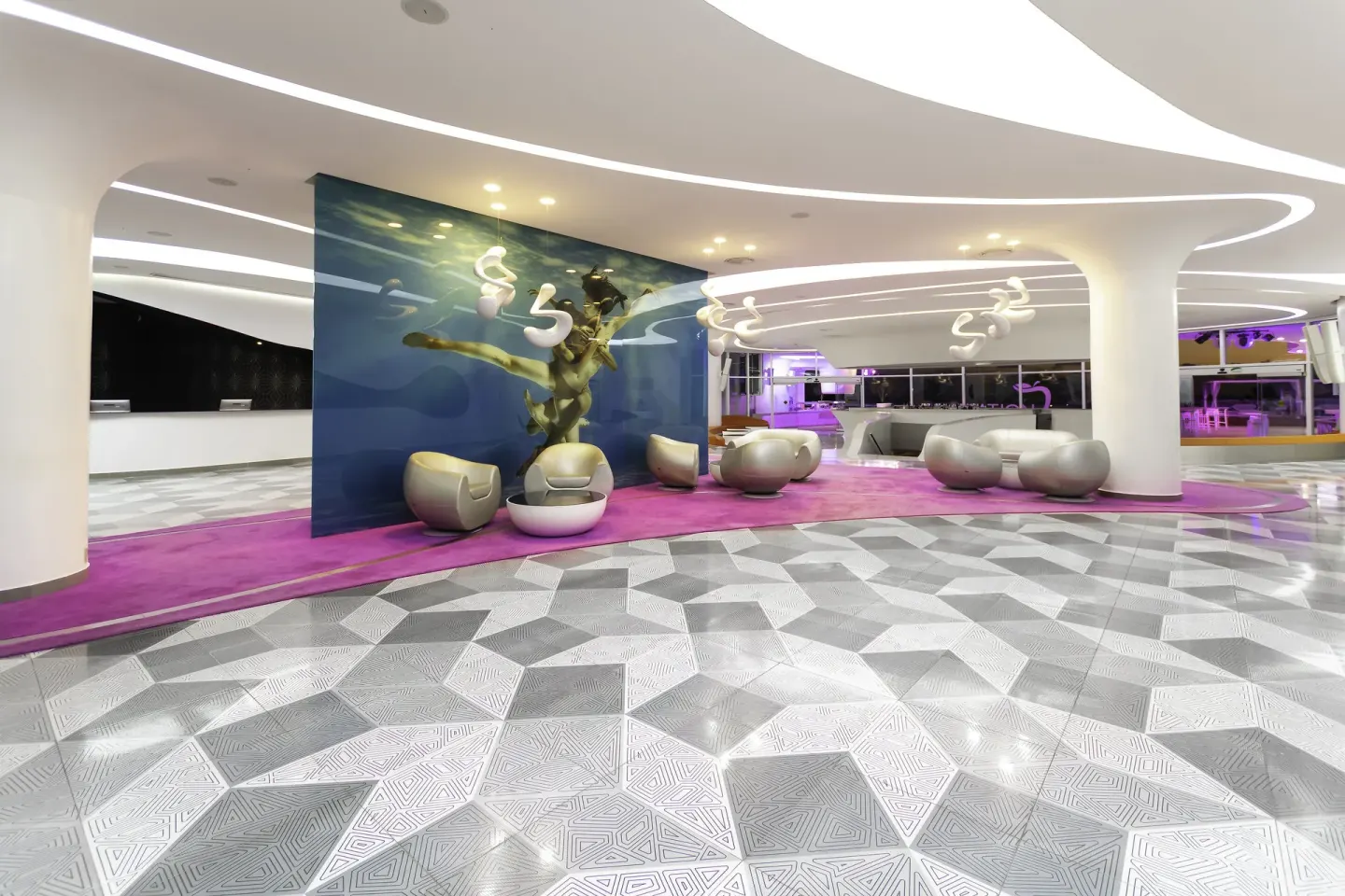 Curved white lobby lounge with purple carpet at Temptation Cancún.