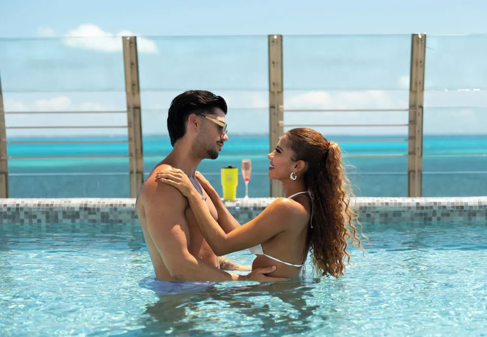 Couple standing together in an ocean-view pool at Temptation Cancún.