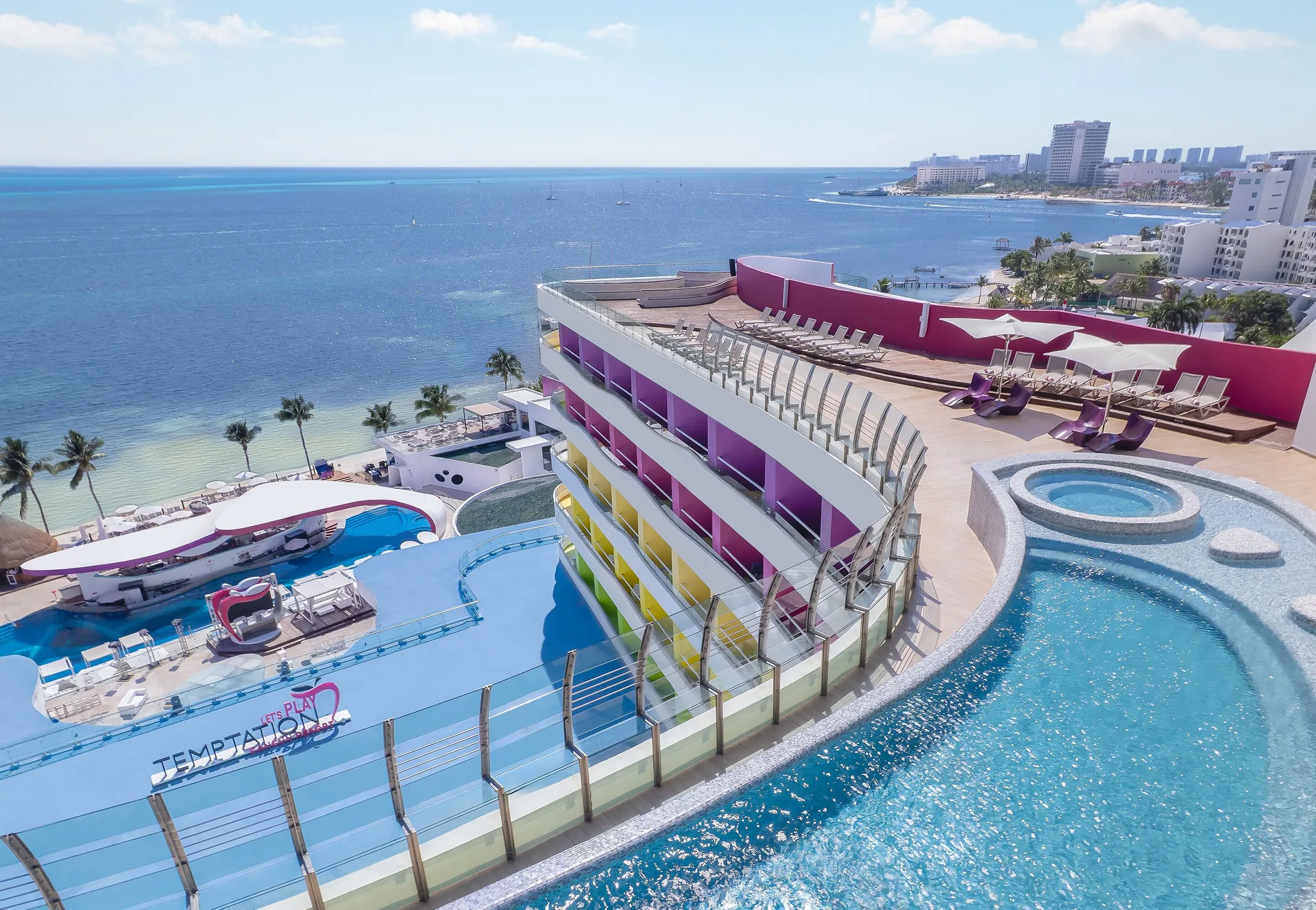 Rooftop pool decks and the shoreline are seen from above at Temptation Cancún.