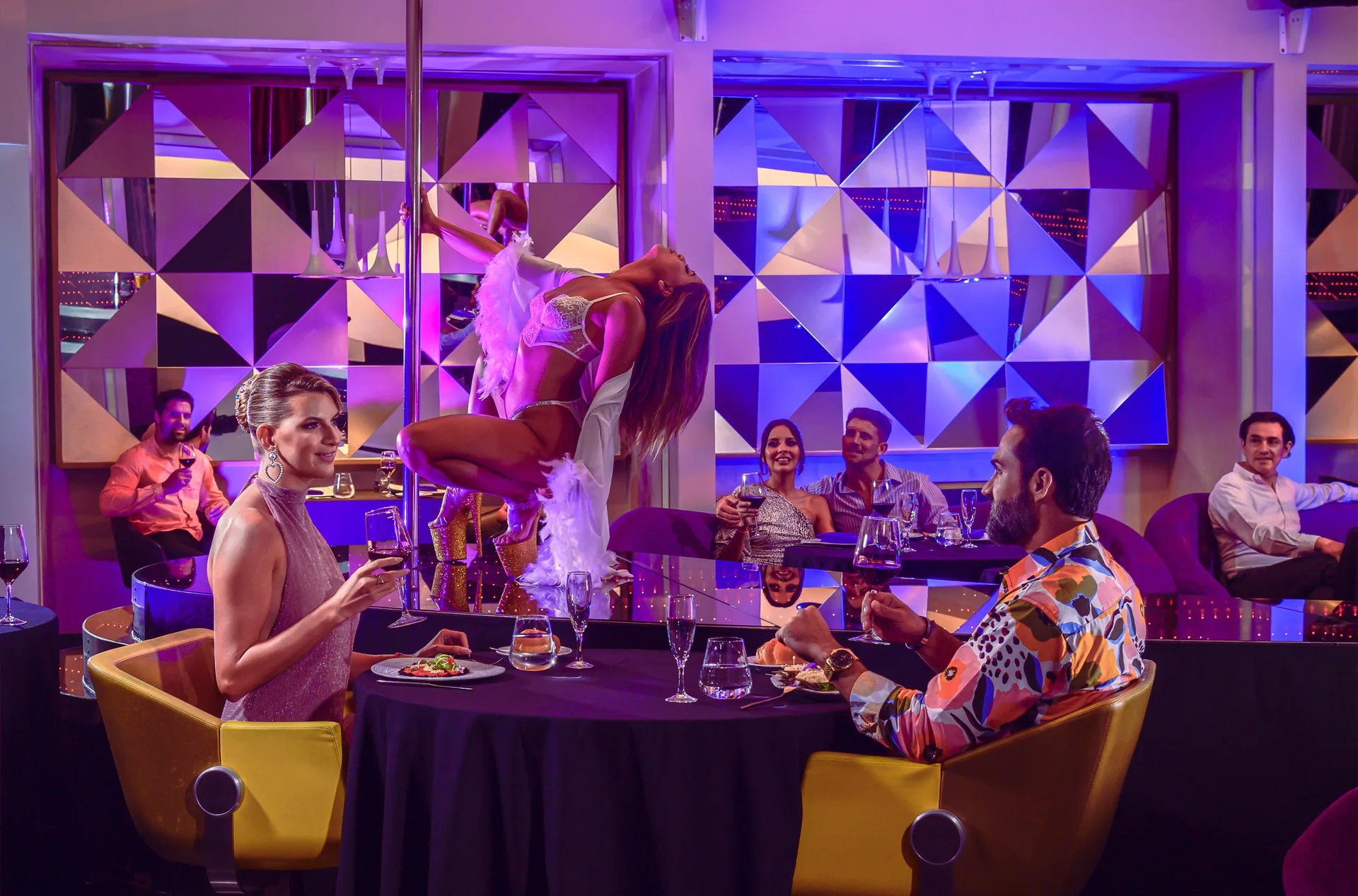 A pole dancer performs beside dining tables at Temptation Cancún.