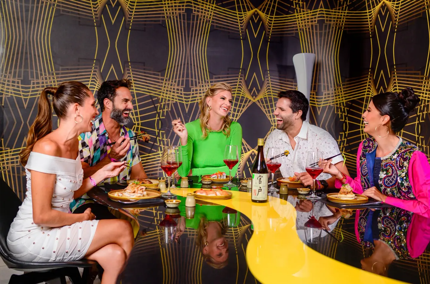 Guests share sushi and drinks at a glossy table at Temptation Cancún.