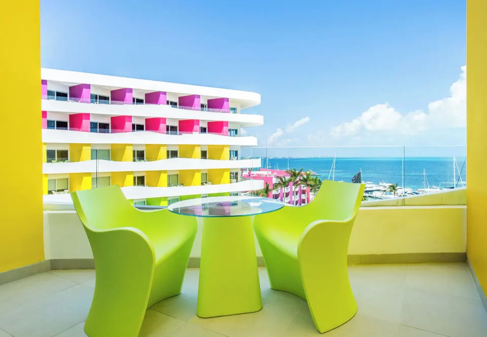 Bash Tower Ocean View balcony at Temptation Cancún with lime chairs, glass table, and sea view.