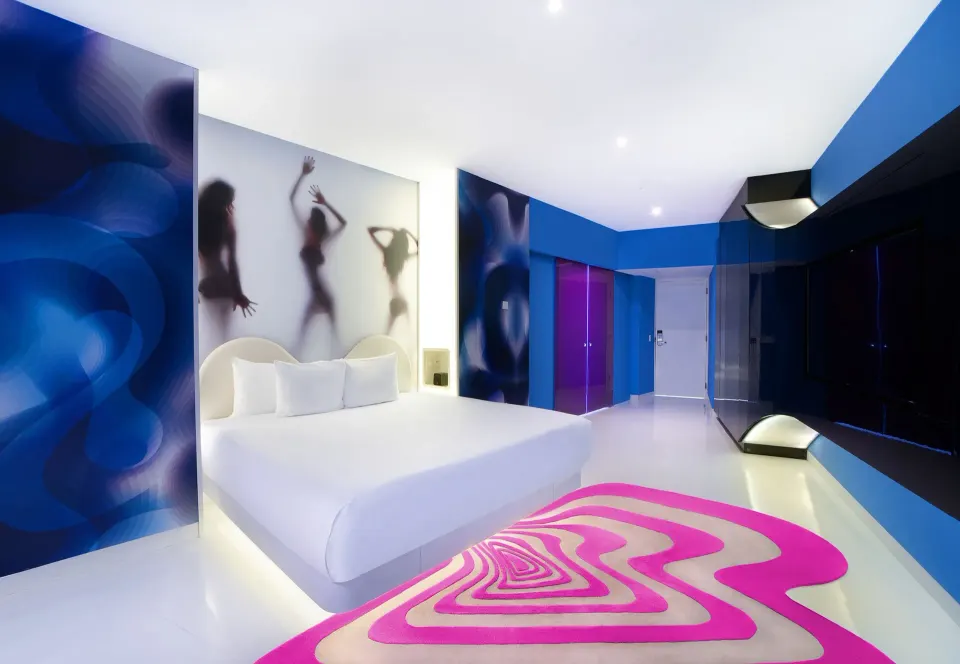 Bash Tower Ocean View king bed guest room at Temptation Cancún with blue walls and pink rug.