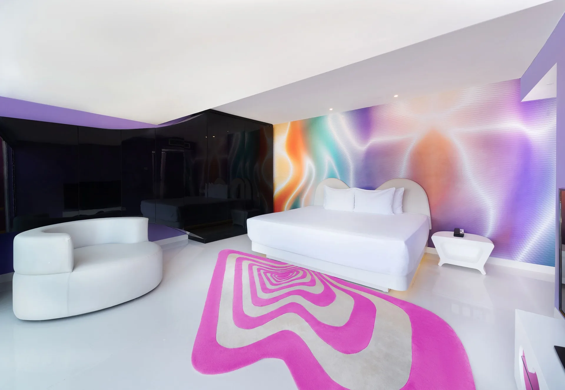 Seduction Beachfront Suite bed, lounge chair, and colorful wall at Temptation at The Tower Cancún.