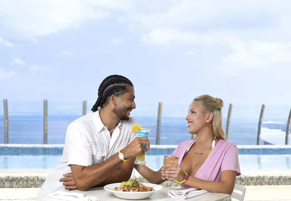 Couple dining by an oceanfront pool at Temptation Cancún.
