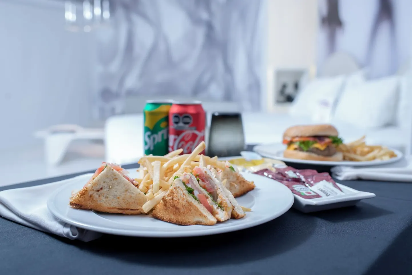 Room-service sandwiches, fries, soda cans, and a burger in a guest room at Temptation at The Tower Cancún.