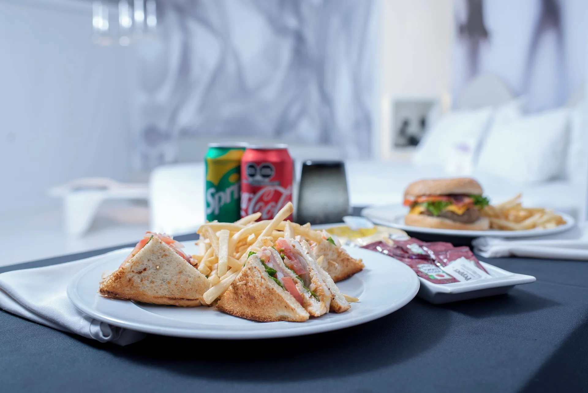 Room-service sandwiches, fries, soda cans, and a burger in a guest room at Temptation at The Tower Cancún.