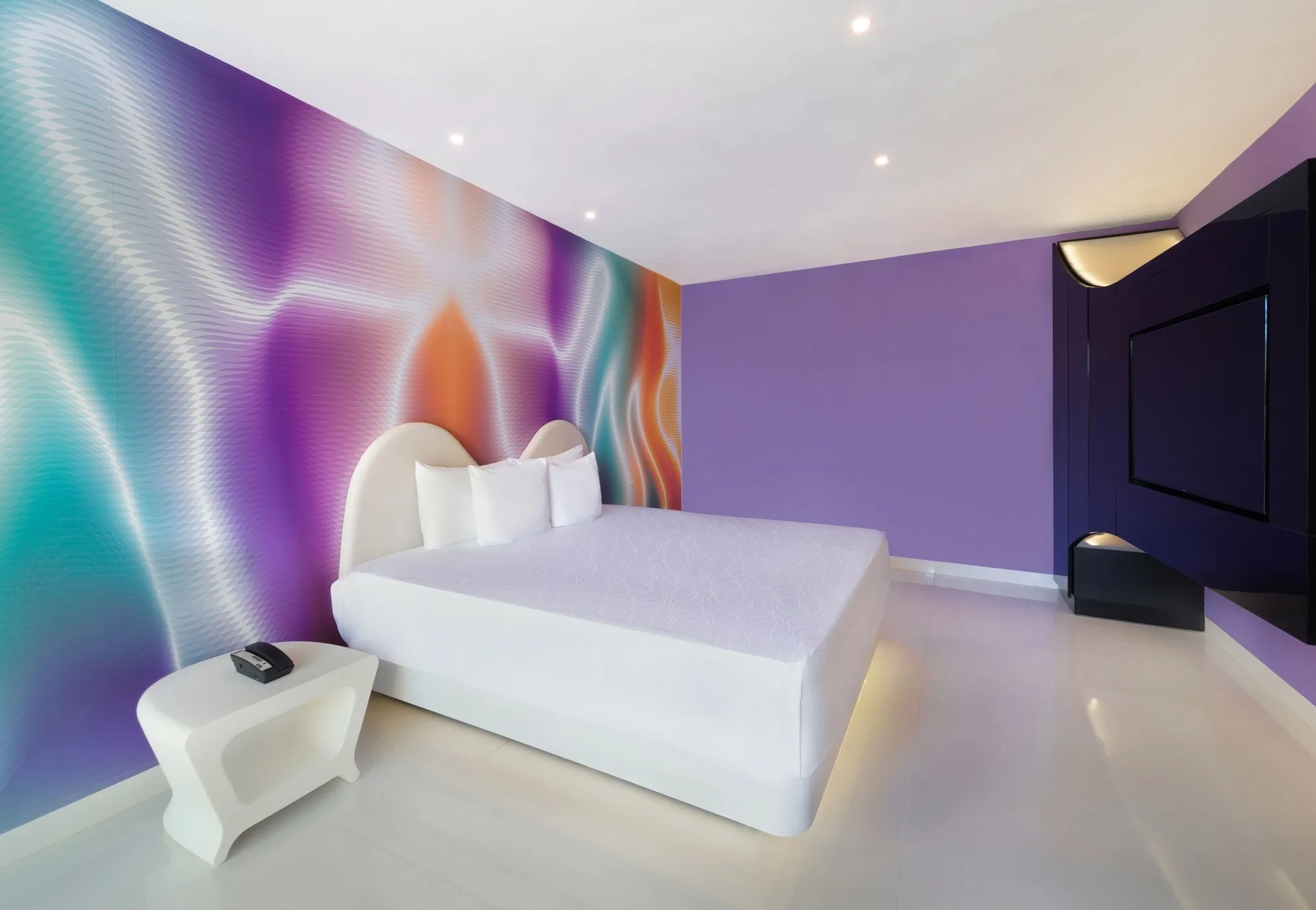 Trendy Room king bed, bedside table, and wall-mounted TV at Temptation at The Tower Cancún.