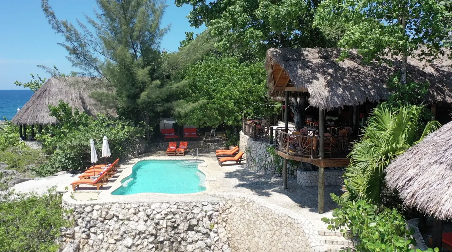 Clifftop pool, thatched roofs and ocean at Tensing Pen Hotel.