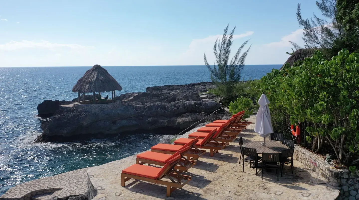 Clifftop sun loungers and a thatched pavilion face the sea at Tensing Pen Hotel.