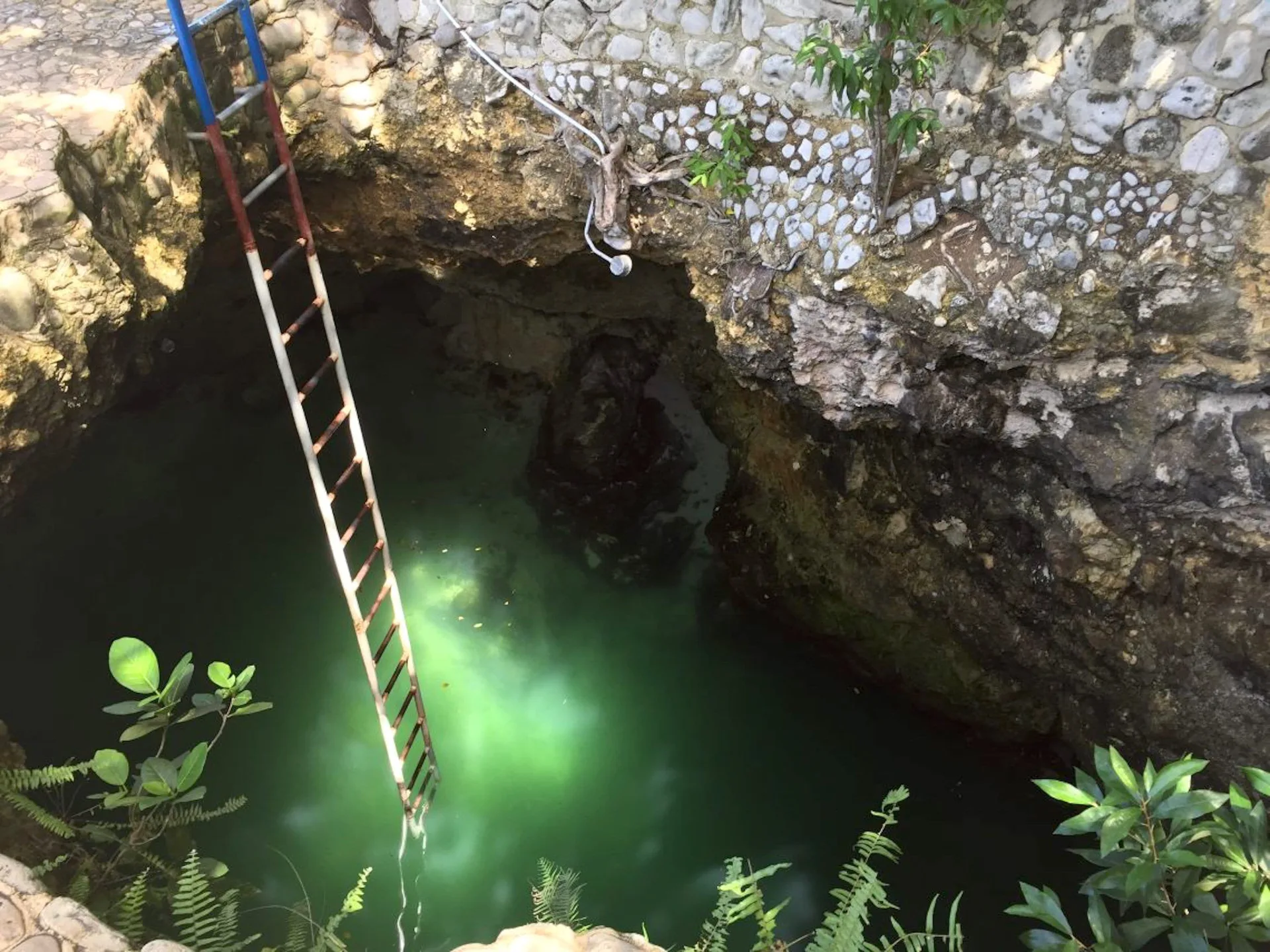 A ladder descends into a rocky cave pool at Tensing Pen Hotel.