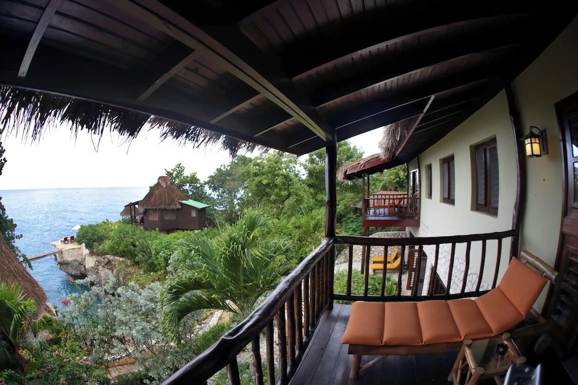 Private balcony with an orange cushioned lounger and sea view at Tensing Pen Hotel.