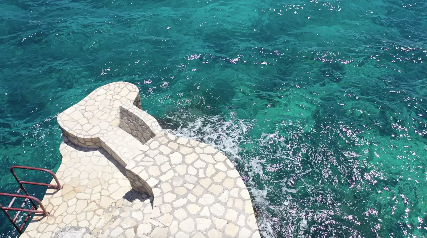 Stone steps descend toward clear turquoise sea water at Tensing Pen Hotel.